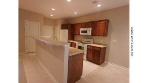 Galley kitchen with wood-tone cabinets, white appliances, and breakfast bar