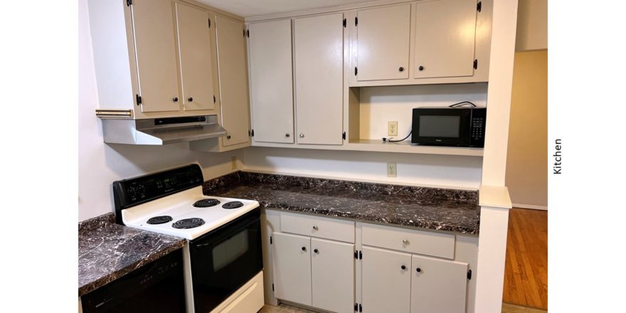 Kitchen with light gray cabinets, white and black range oven, black microwave, and black dishwasher