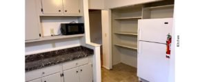 Kitchen with light gray cabinets, black microwave and white fridge