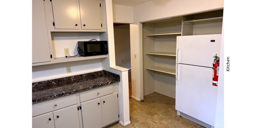 Kitchen with light gray cabinets, black microwave and white fridge