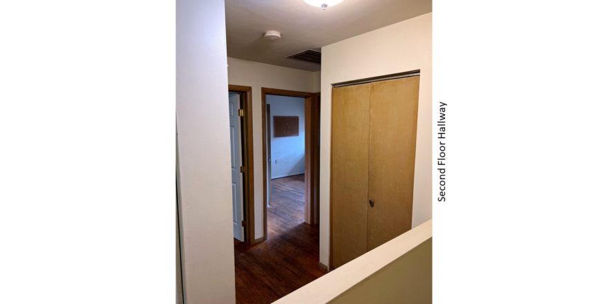 Hallway with closet and hardwood floors