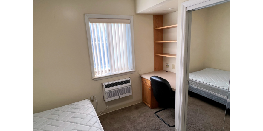 Bedroom with built in desk, closet, bed, window, and air conditioner