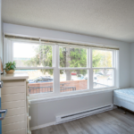Room with large windows, dresser, and bed