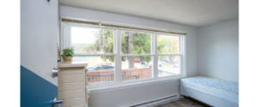 Room with large windows, dresser, and bed