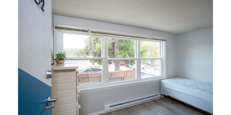 Room with large windows, dresser, and bed