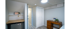 Room with mini-fridge, countertop, shelf, desk, and bed