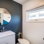 Bathroom with mirror, vanity, toilet and window