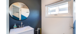 Bathroom with mirror, vanity, toilet and window