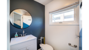 Bathroom with mirror, vanity, toilet and window