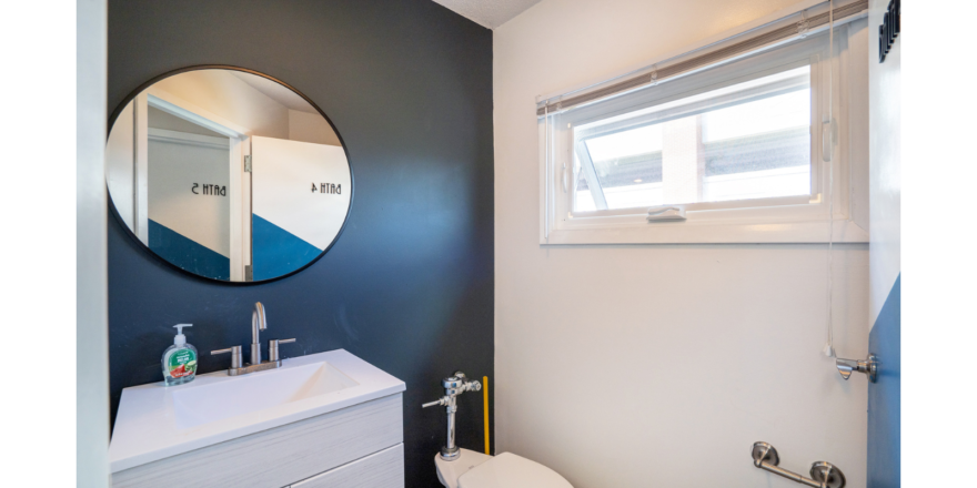 Bathroom with mirror, vanity, toilet and window