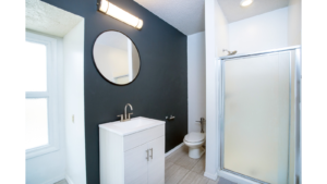 Bathroom with mirror, vanity, toilet, and shower stall