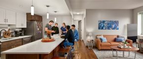 Friends hanging out at a kitchen island next to a decorated living room