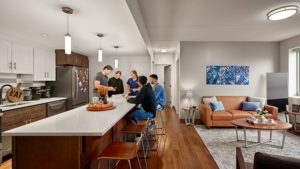 Friends hanging out at a kitchen island next to a decorated living room