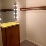 Owner's suite closet with small counter top and mirror with lighting