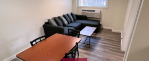 Living room with laminate flooring, dining table, coffee table, air conditioner, and sofa