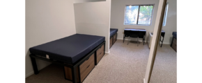 Bedroom with full-size beds, desk with chair, and small dressers