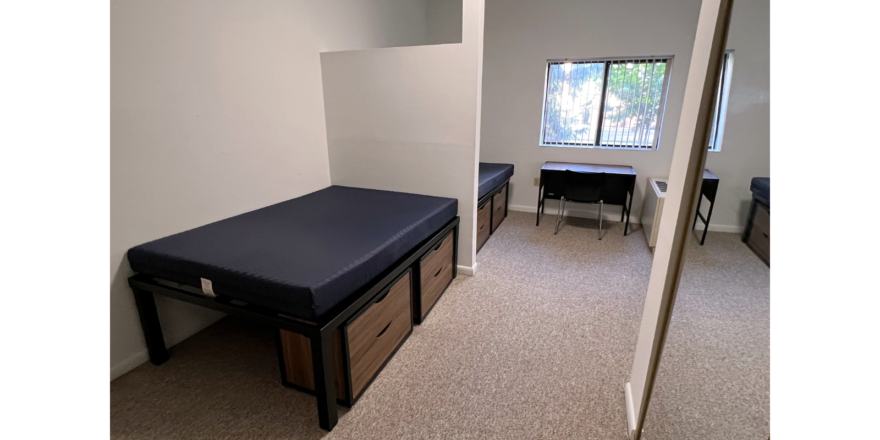 Bedroom with full-size beds, desk with chair, and small dressers