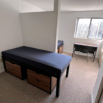 Bedroom with twin-size beds, desk with chair, and small dressers