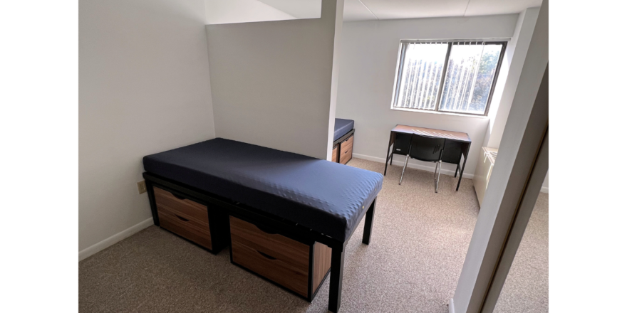 Bedroom with twin-size beds, desk with chair, and small dressers