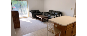 Kitchen with wood-tone cabinets, island, and living room with sofa, loveseat, coffee table, TV stand, and end tables