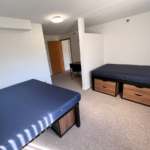Bedroom with full-size beds, desk with chair, and small dressers