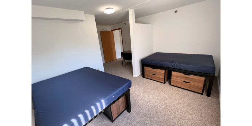 Bedroom with full-size beds, desk with chair, and small dressers