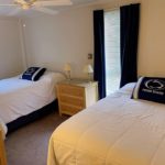 Bedroom with beds, dressers, lamps, ceiling fan, blinds, and curtains