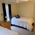 Bedroom with beds, dressers, lamps, ceiling fan, blinds, and curtains