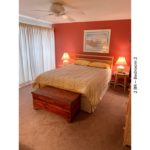 Bedroom with bed, night stands, lamps, chest, painting, ceiling fan, and curtains