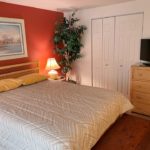 Bedroom with bed, night stand, lamp, chest, painting, ceiling fan, fake plant, tv, and dresser