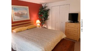 Bedroom with bed, night stand, lamp, chest, painting, ceiling fan, fake plant, tv, and dresser