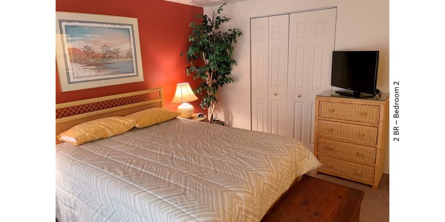 Bedroom with bed, night stand, lamp, chest, painting, ceiling fan, fake plant, tv, and dresser