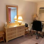 Bedroom with desk, desk chair, end tables, dresser with mirror, and lamps