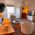 Living room with arm chairs, couch, lamps, end tables, coffee table, ceiling fan, and slider to balcony
