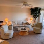 Living room with arm chairs, end tables, lamps, coffee table, couch, and fake plant