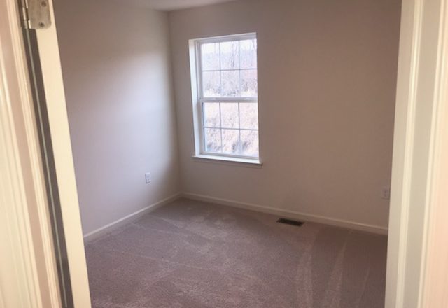 an empty room with carpet and a window