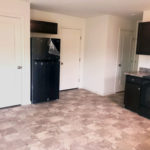 an empty kitchen with black appliances and white walls