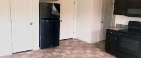 an empty kitchen with black appliances and white walls