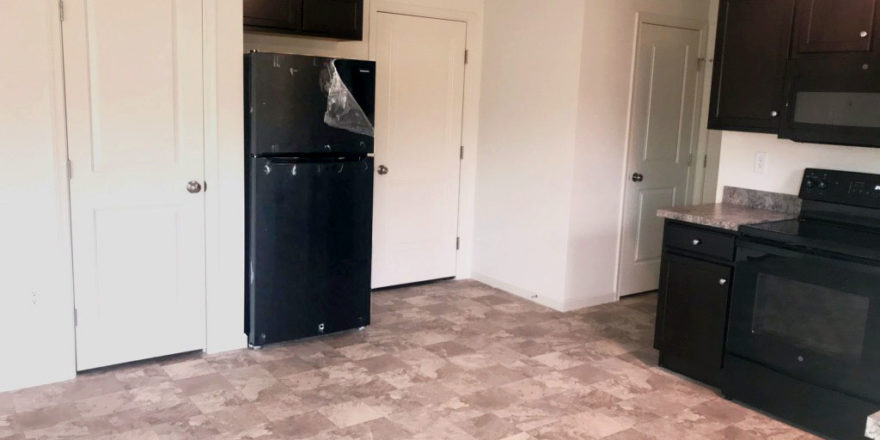 an empty kitchen with black appliances and white walls