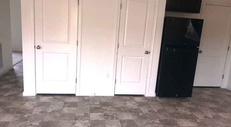a room with three white doors and a black refrigerator