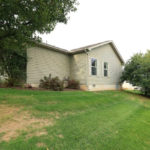 Exterior rear of home with pastel green siding and large yard