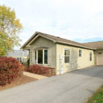 Exterior side of house with pastel green siding, large bay window, and side windows