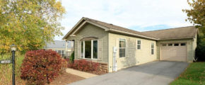 Exterior side of house with pastel green siding, large bay window, and side windows