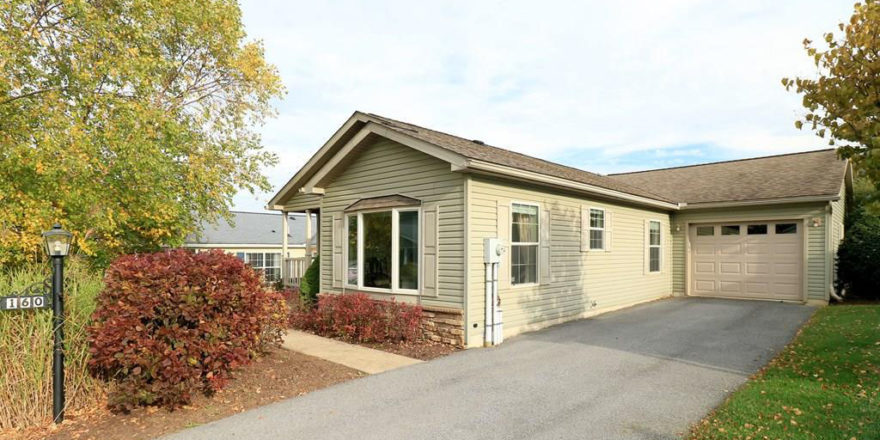 Exterior side of house with pastel green siding, large bay window, and side windows