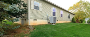 Exterior side of home with pastel green siding, four windows with green shutter trim, large yard, and hvac unit