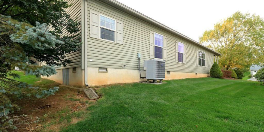 Exterior side of home with pastel green siding, four windows with green shutter trim, large yard, and hvac unit