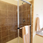 a bathroom with a glass shower door and tiled walls