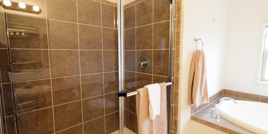 a bathroom with a glass shower door and tiled walls