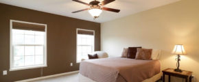 a bedroom with a ceiling fan and two windows