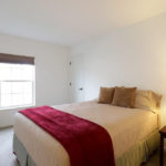 a bedroom with a bed, nightstand and window